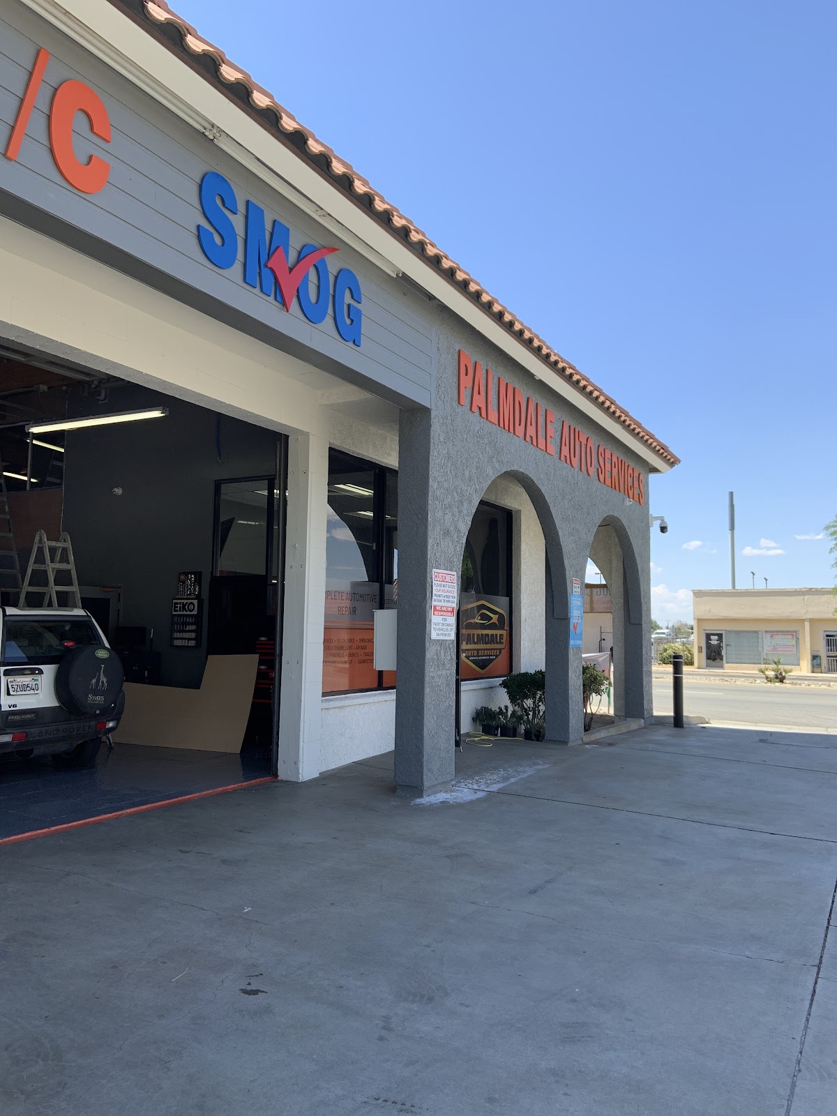 The Palmdale Auto Services storefront with the large Smog sign above an open bay