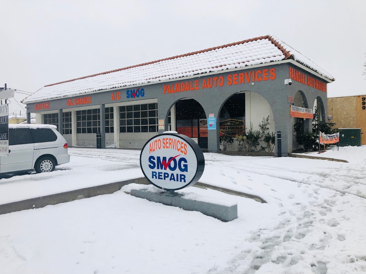 Palmdale Auto Services under snow, with the round Auto Services Smog Repair sign in the foreground